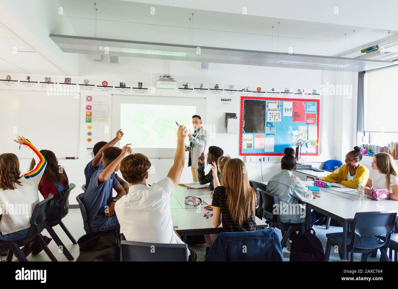 Insegnante di scuola superiore che chiama gli studenti con le mani alzate durante la lezione in classe Foto Stock