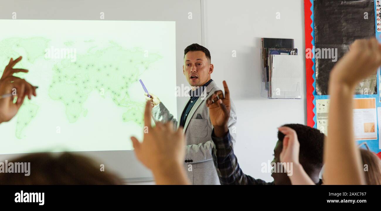 Insegnante di scuola superiore maschile che conduce la lezione sullo schermo di proiezione in classe Foto Stock