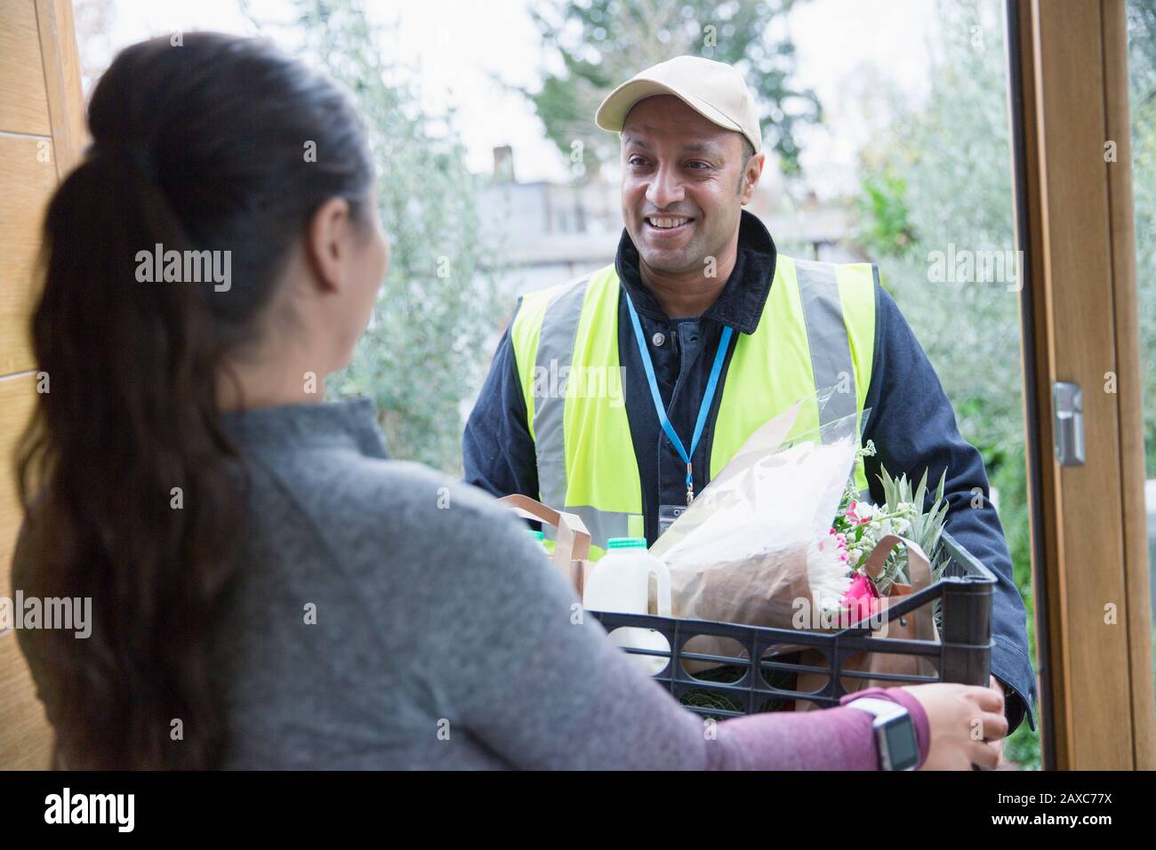 Donna saluto cibo deliveryman a porta d'ingresso Foto Stock