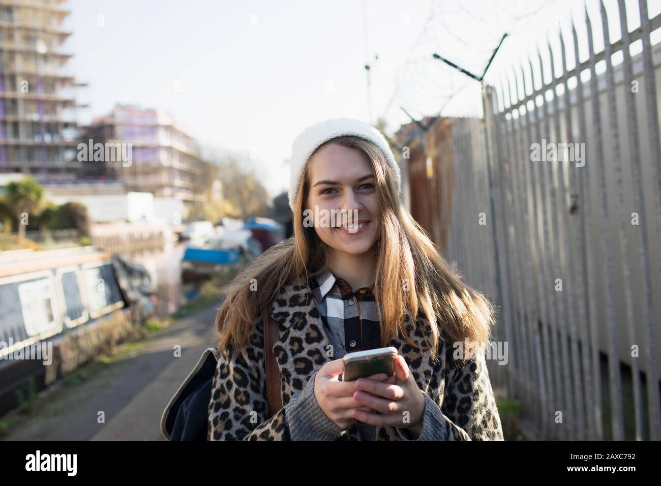 Ritratto giovane donna sorridente con smartphone sul marciapiede urbano Foto Stock