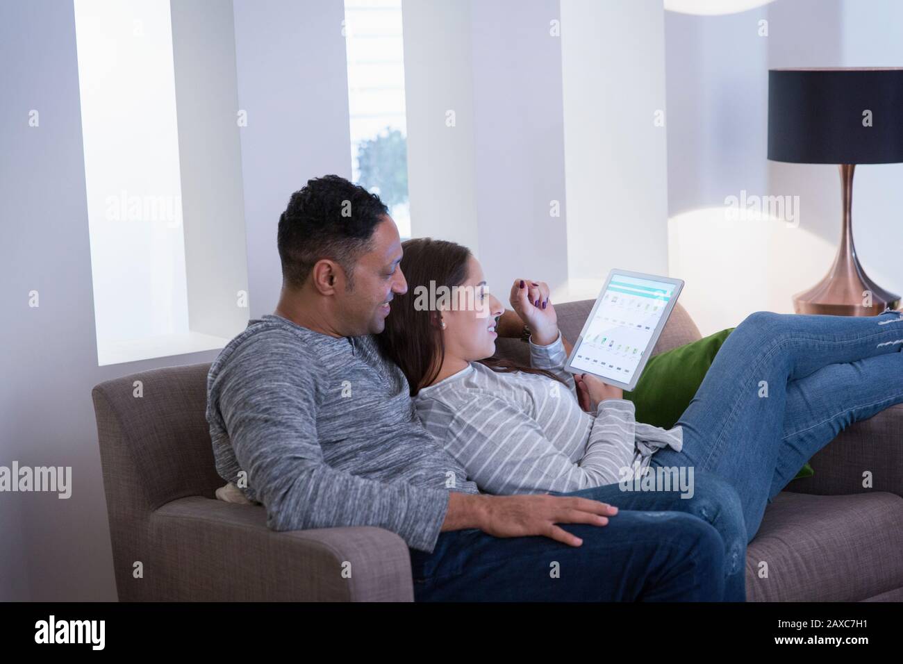 Coppia rilassante, utilizzando un tablet digitale sul divano del soggiorno Foto Stock
