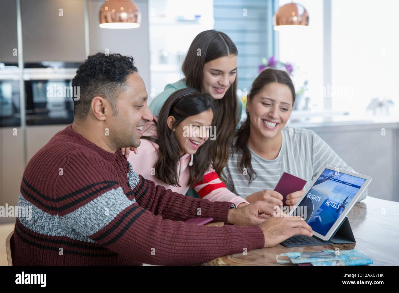 Felice famiglia pianificazione vacanza al tablet digitale in cucina Foto Stock