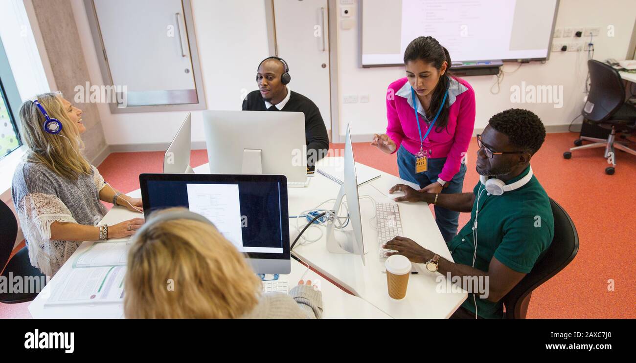 Istruttore universitario della Comunità che aiuta gli allievi ai calcolatori nella classe di laboratorio del calcolatore Foto Stock