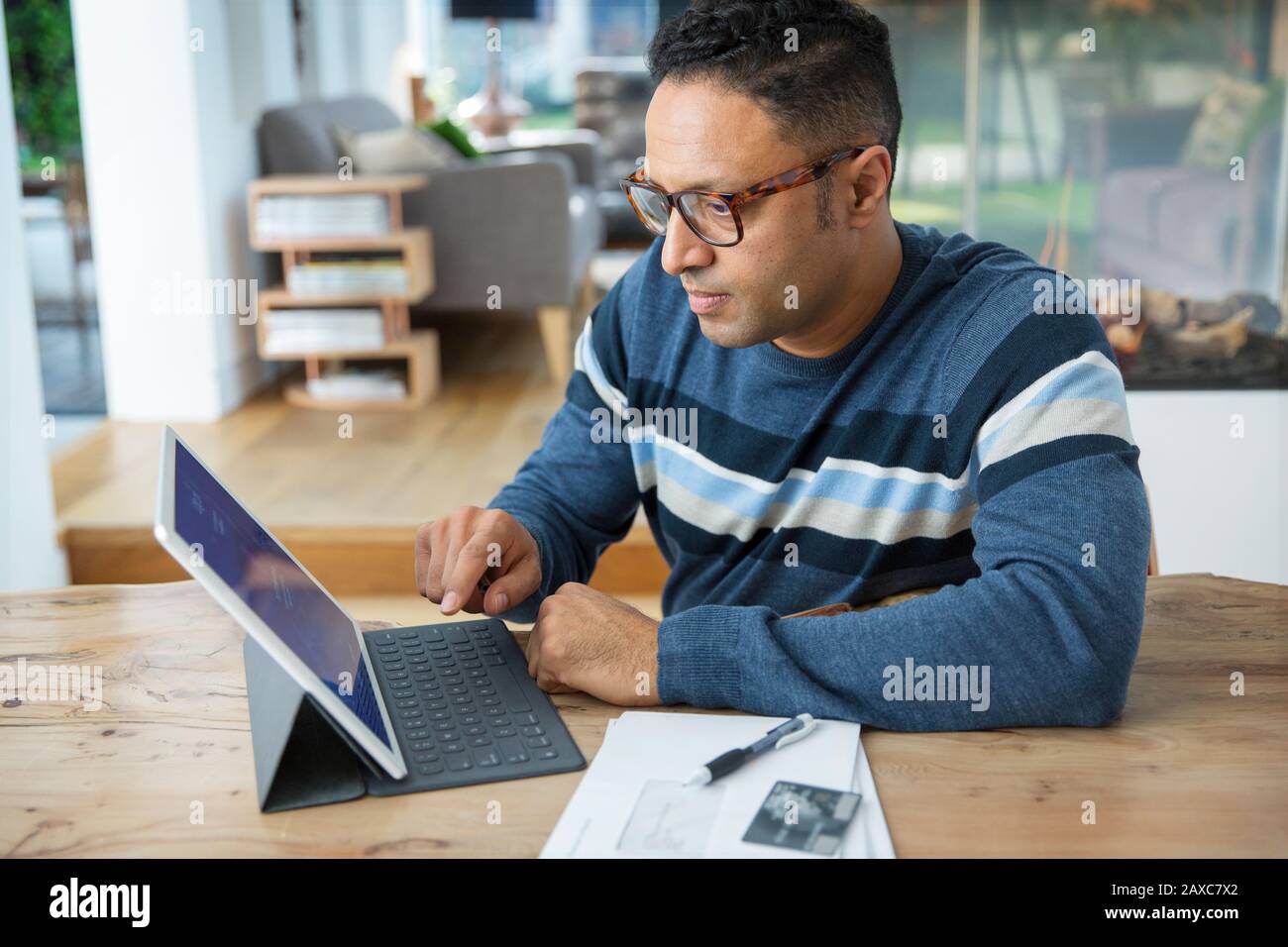Uomo concentrato che paga le fatture al tablet digitale Foto Stock
