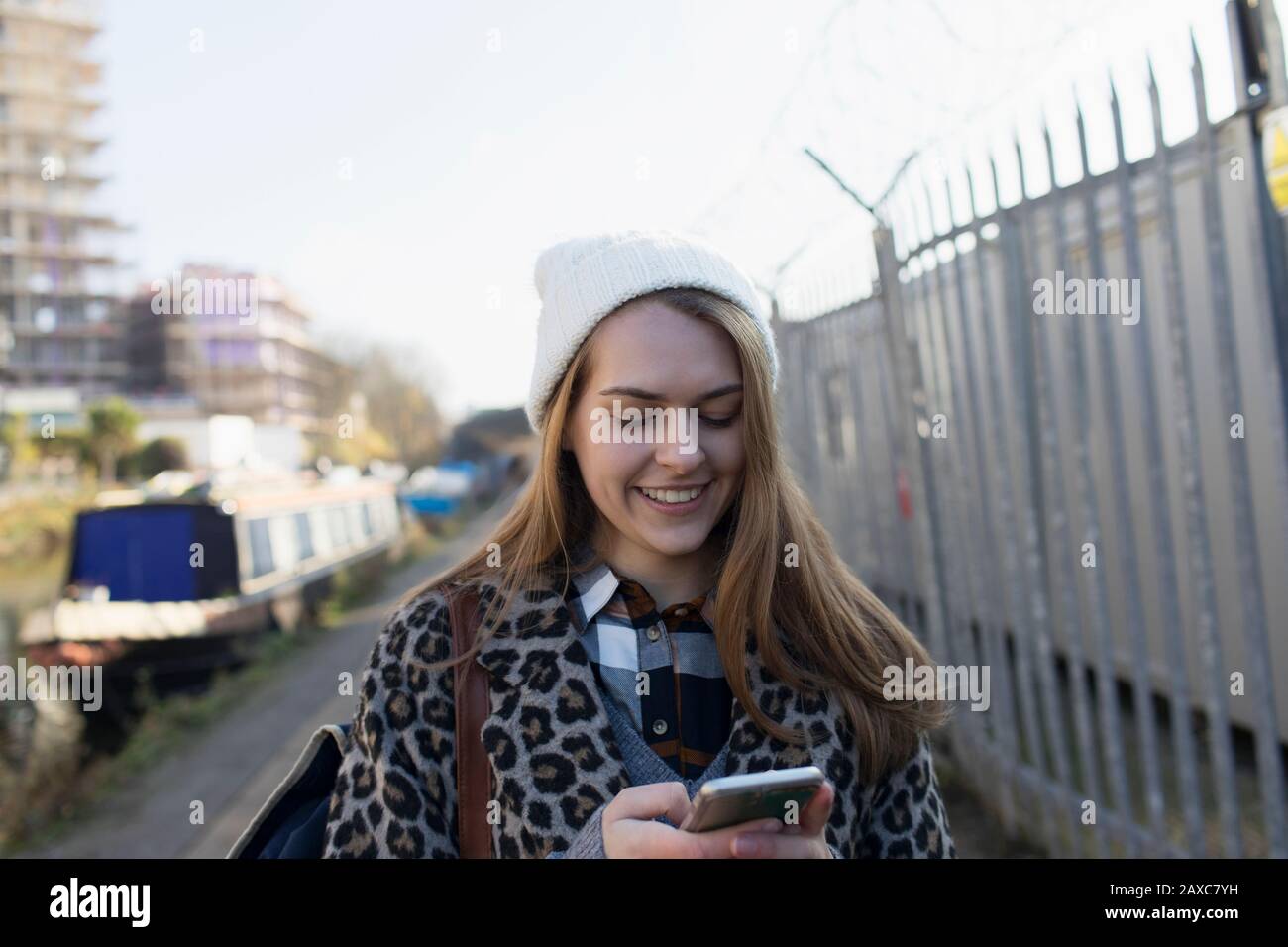Giovane donna che usa lo smartphone lungo il canale Foto Stock