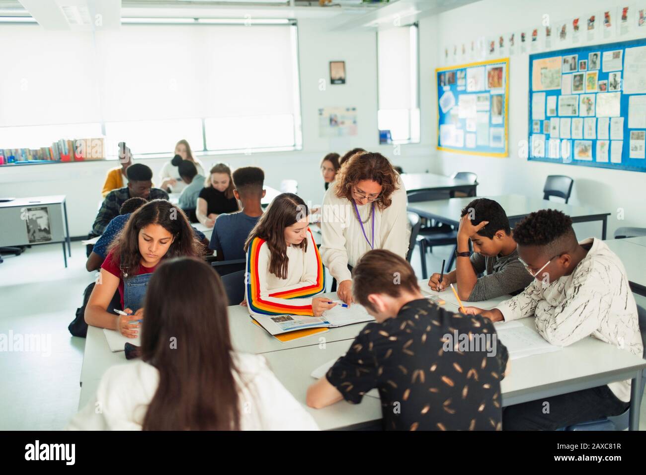 Insegnante di scuola superiore che aiuta gli studenti a studiare in classe Foto Stock