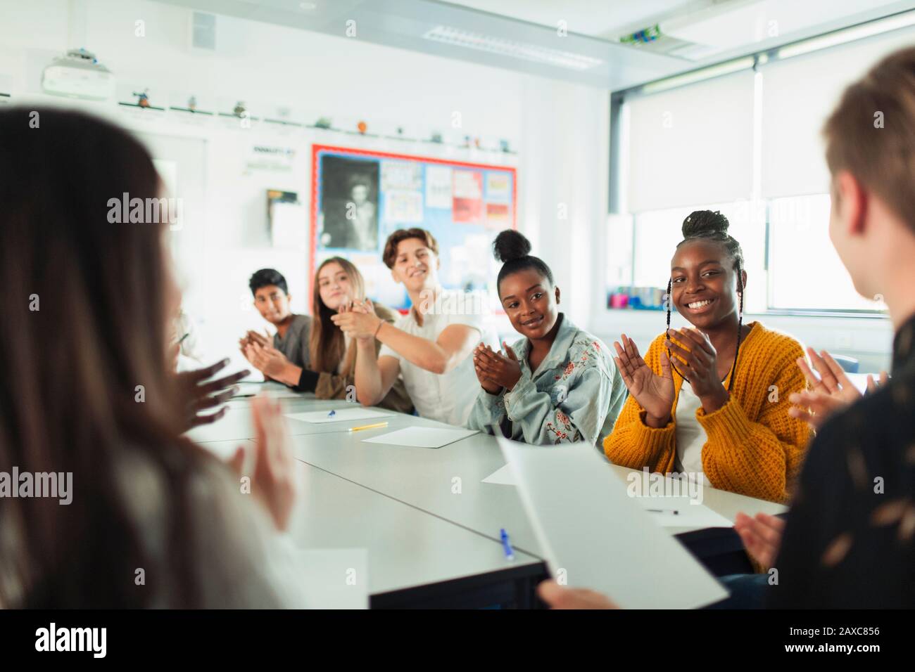 Gli studenti delle scuole superiori felici che battano nella classe di discussione Foto Stock