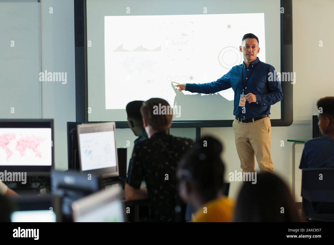 Insegnante di alto livello maschile che conduce la lezione sullo schermo di proiezione in classe Foto Stock