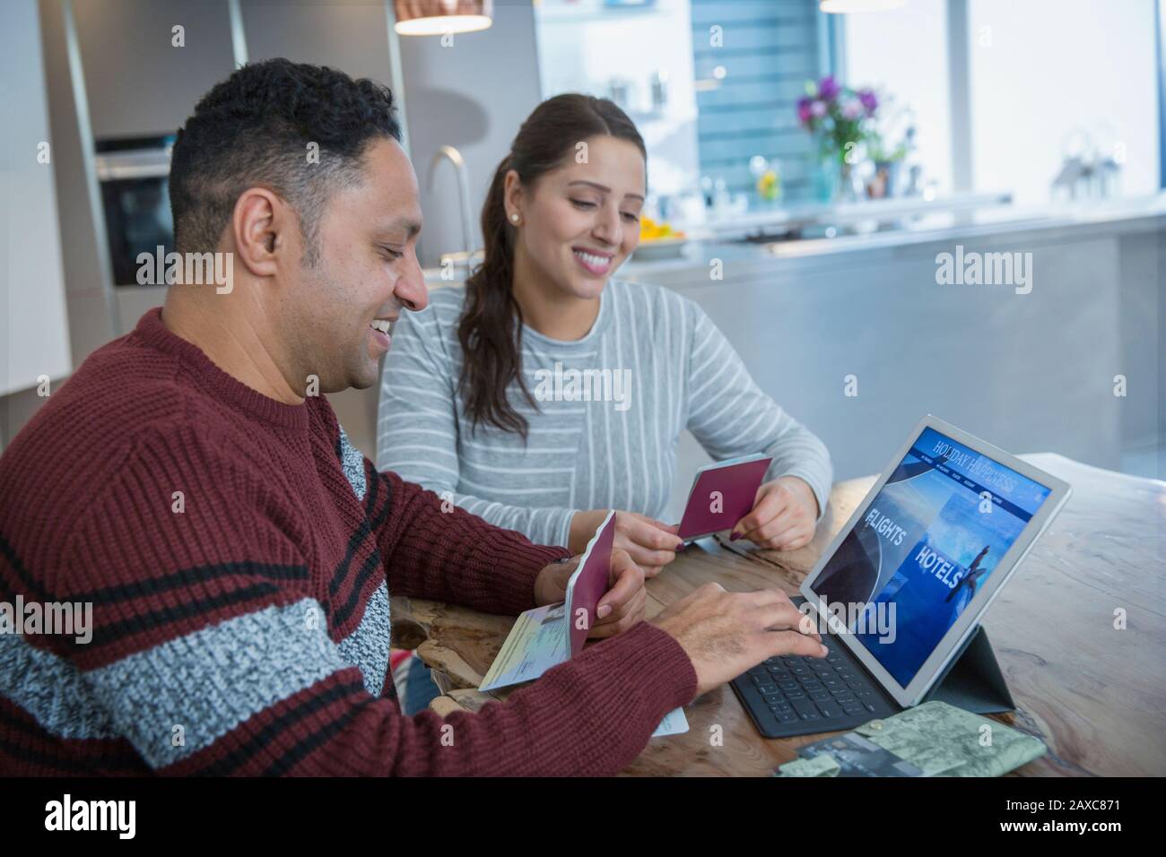 Felice coppia con passaporti pianificazione vacanza al tablet digitale Foto Stock