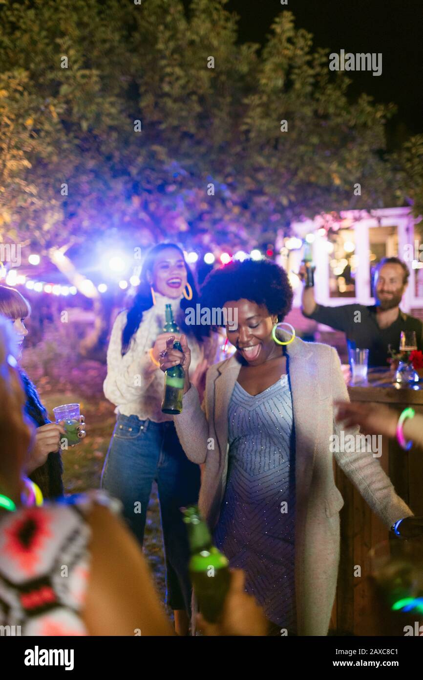 Amici felici che ballano e bevono a festa in giardino Foto Stock