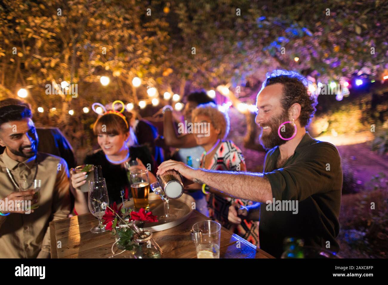 Uomo che fa cocktail per gli amici al party in giardino Foto Stock