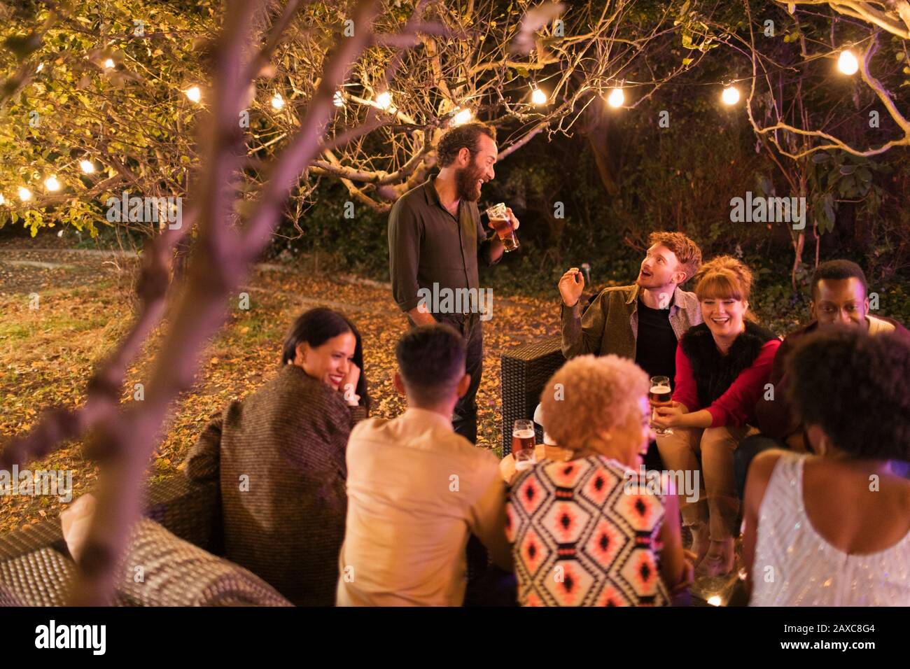 Amici che parlano e bevono a festa in giardino Foto Stock