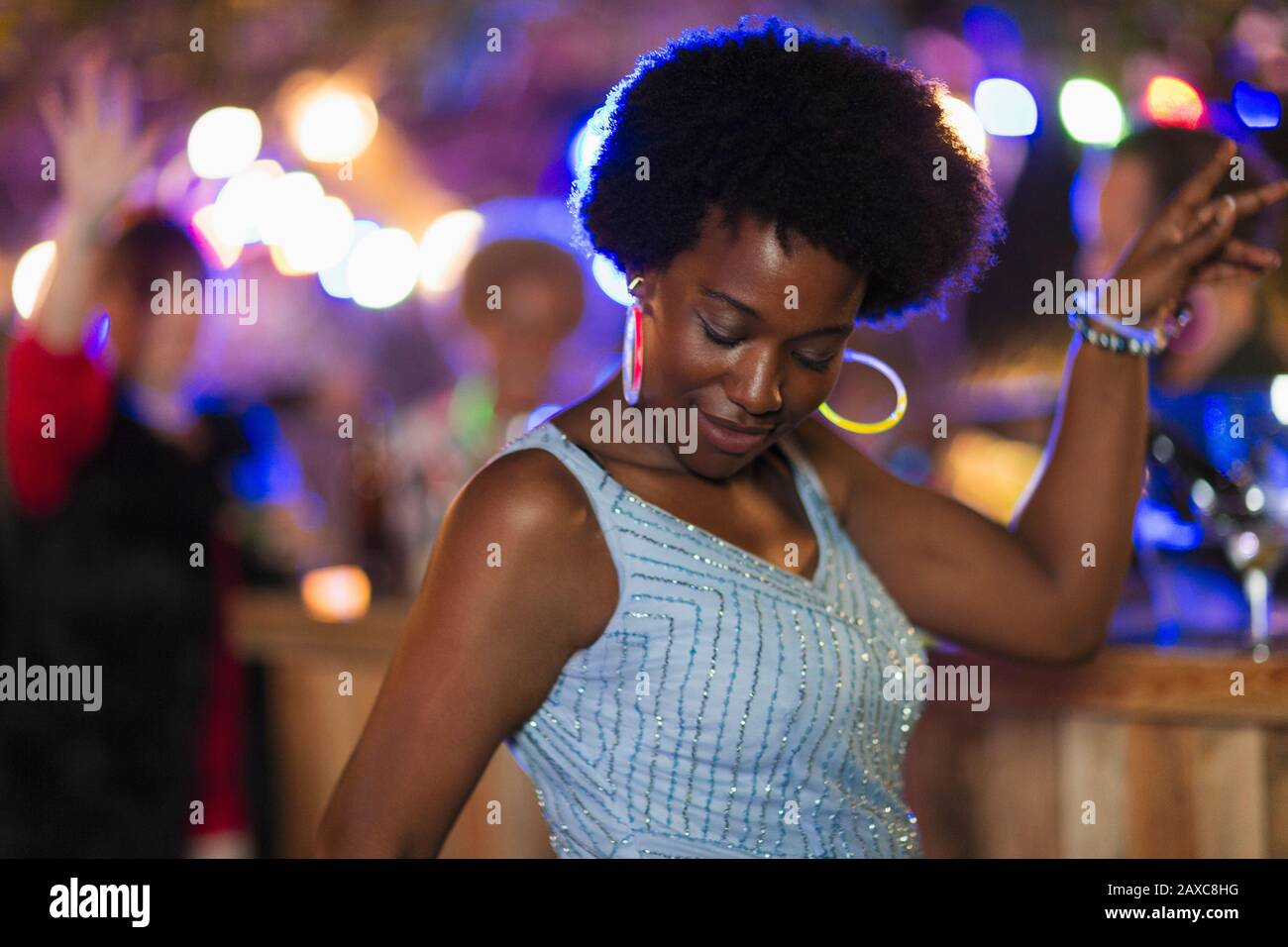 Donna spensierata con orecchini al neon che ballano a festa Foto Stock