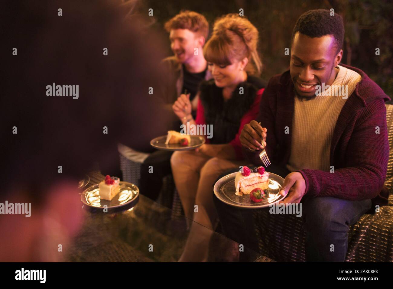 Gli amici festeggiano il compleanno, mangiando la torta sul patio Foto Stock