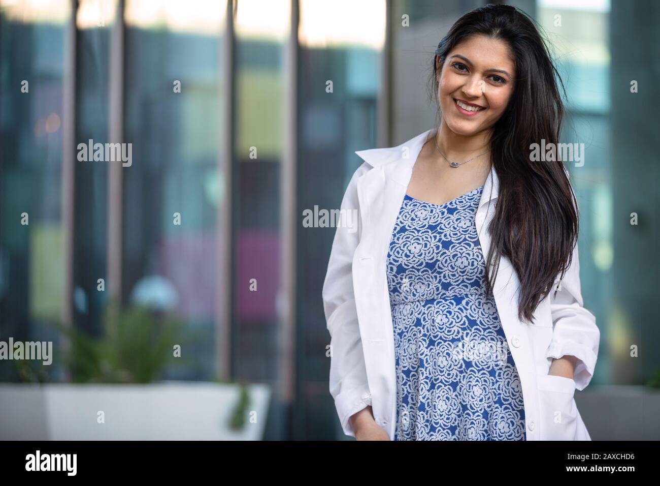 Professionista medico indiano americano in un cappotto bianco all'ufficio del posto di lavoro, possibilmente dentista, terapista, farmacista Foto Stock