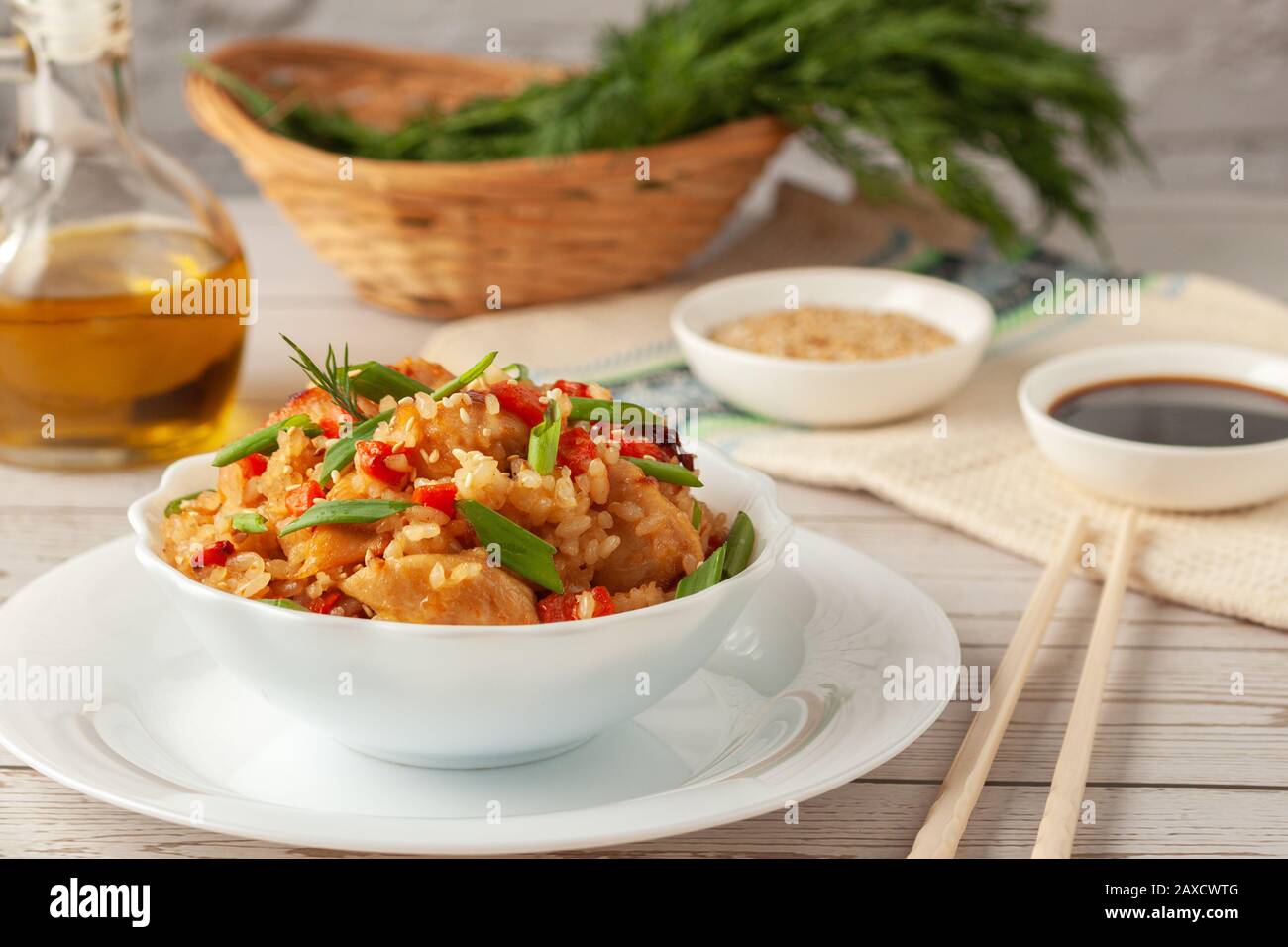 Tori chahan riso giapponese fritto con verdure e pollo in salsa di soia in una piastra nera su un tavolo di legno Foto Stock