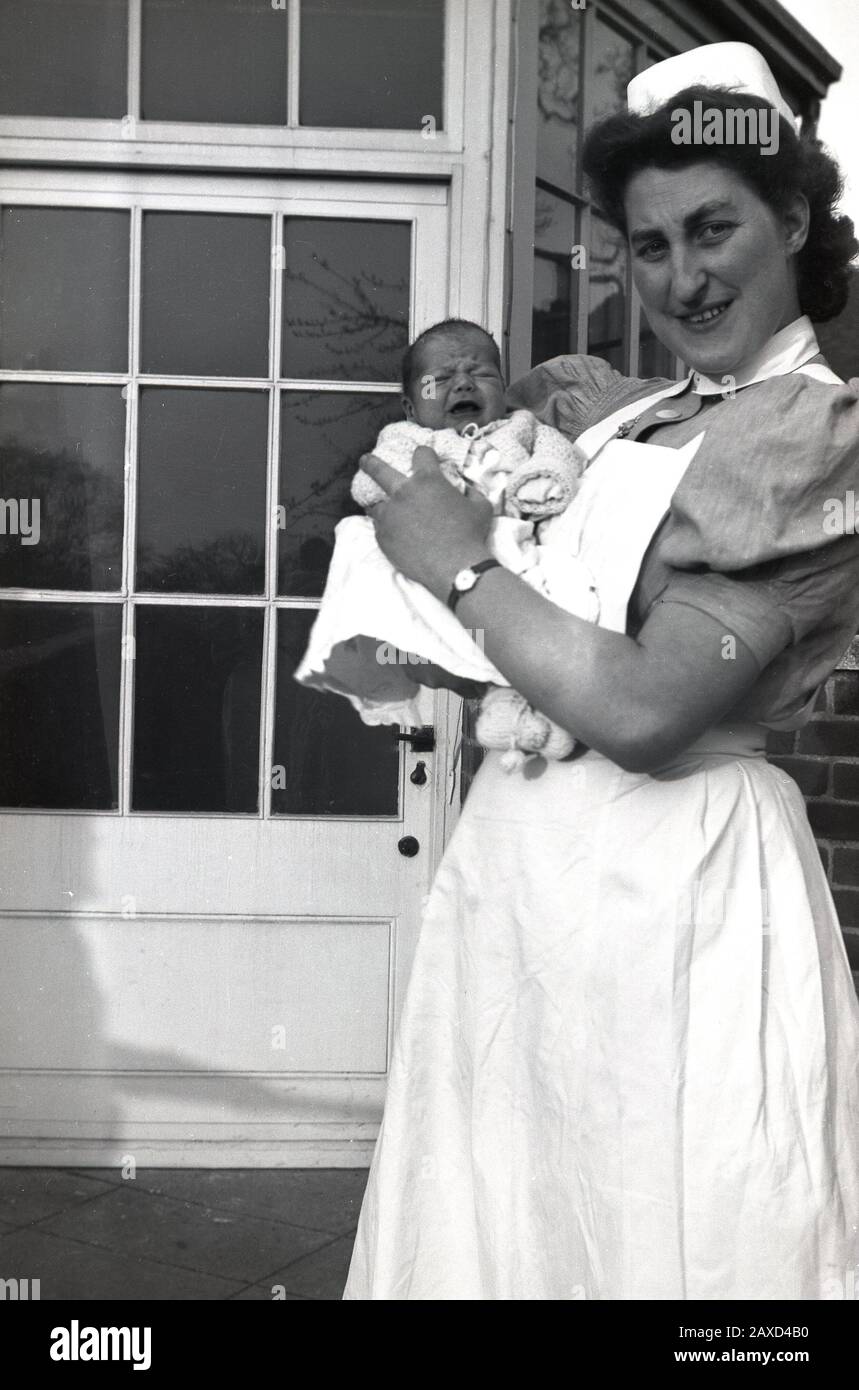 Anni '1940, storica, un'infermiera di maternità in uniforme con un neonato, Inghilterra, Regno Unito. Foto Stock