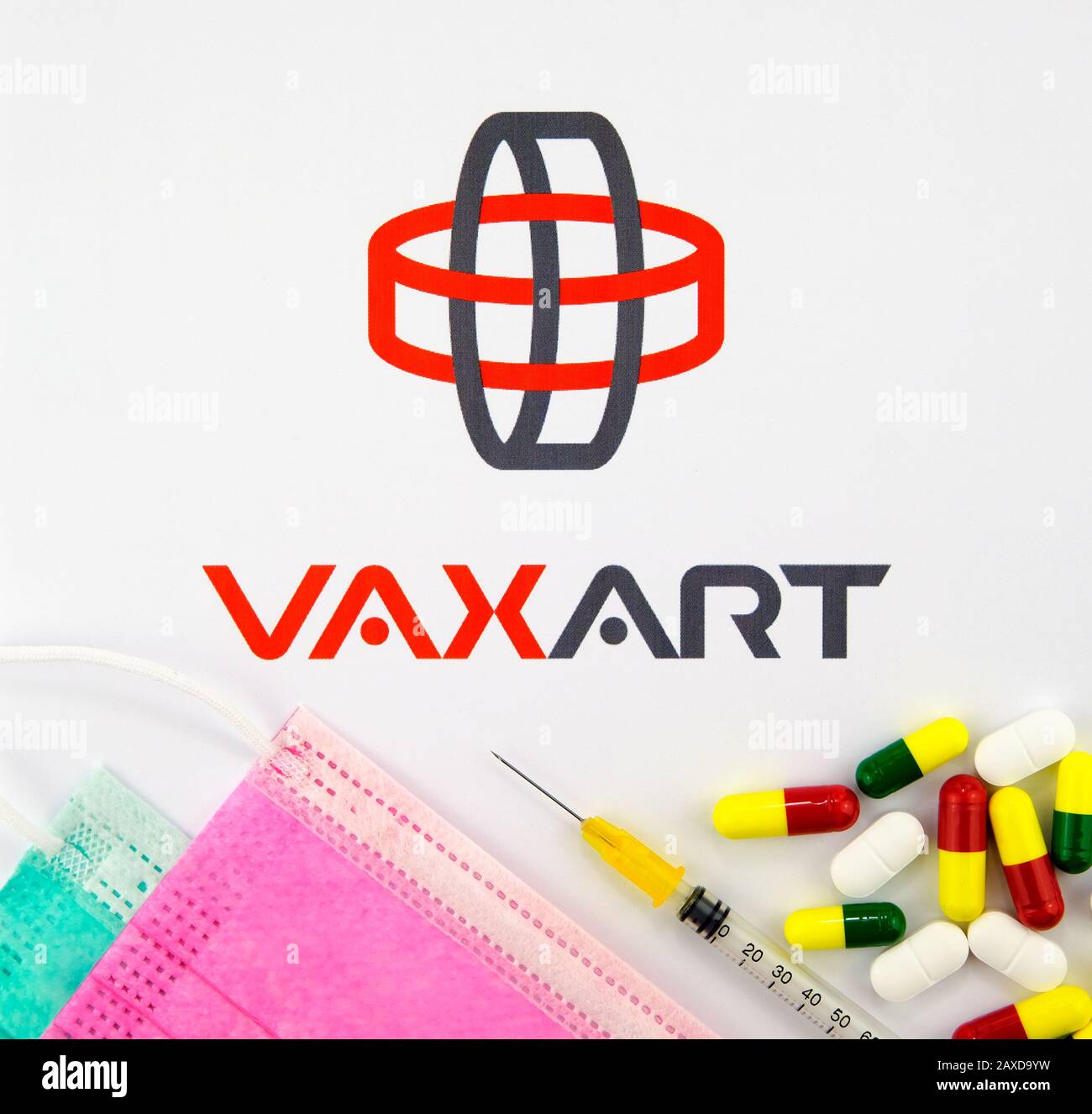 Logo aziendale VAXART visto sulla brochure con le maschere virali, siringa e pillole. Concept foto. Disposizione piatta. Foto Stock