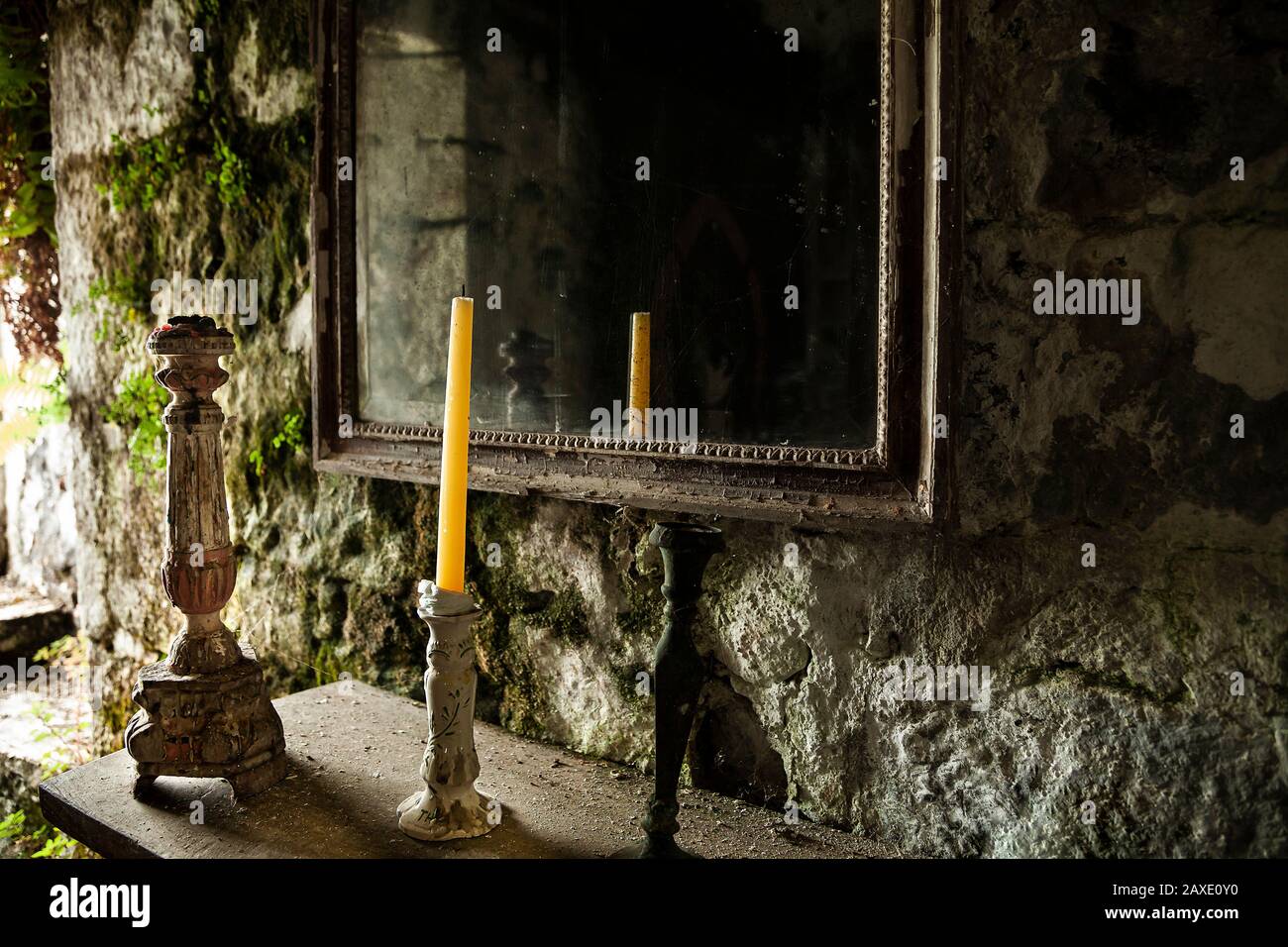 Supporti per candele e specchio nella stanza mossy murata Foto Stock