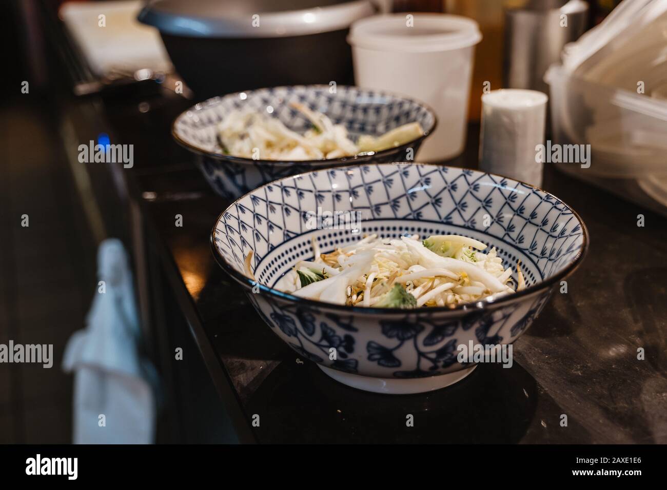 Vista di messa a fuoco selezionata, preparazione di noodle di riso, germoglio di fagioli e verdure in ciotole con motivo blu cinese, sul banco alla cucina del ristorante. Foto Stock