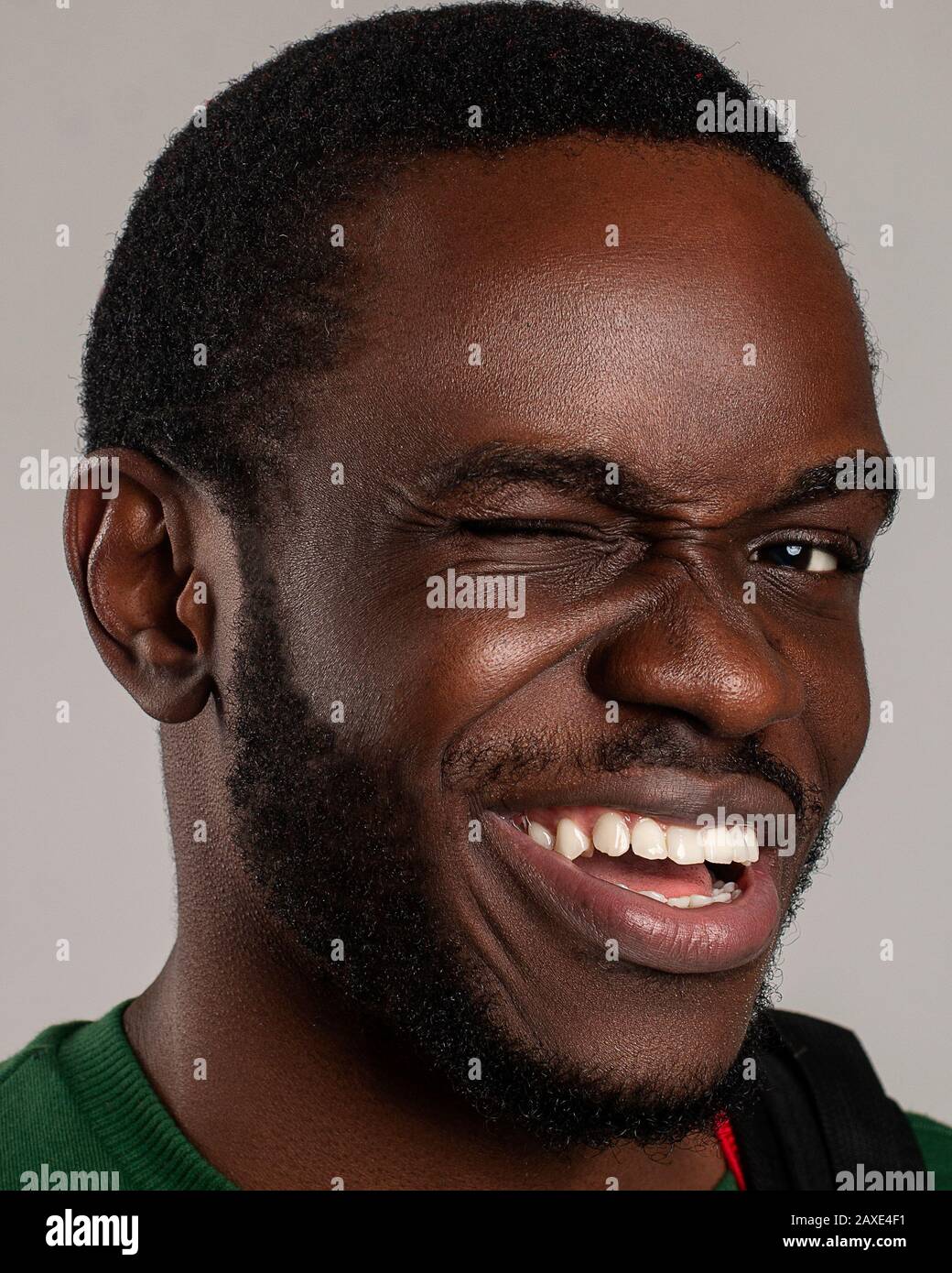 Ritratto di un giovane maschio africano americano Sorridente, Eccitato e mostrando atteggiamento positivo con un occhiolino e denti belli mentre si affaccia la fotocamera felice Foto Stock