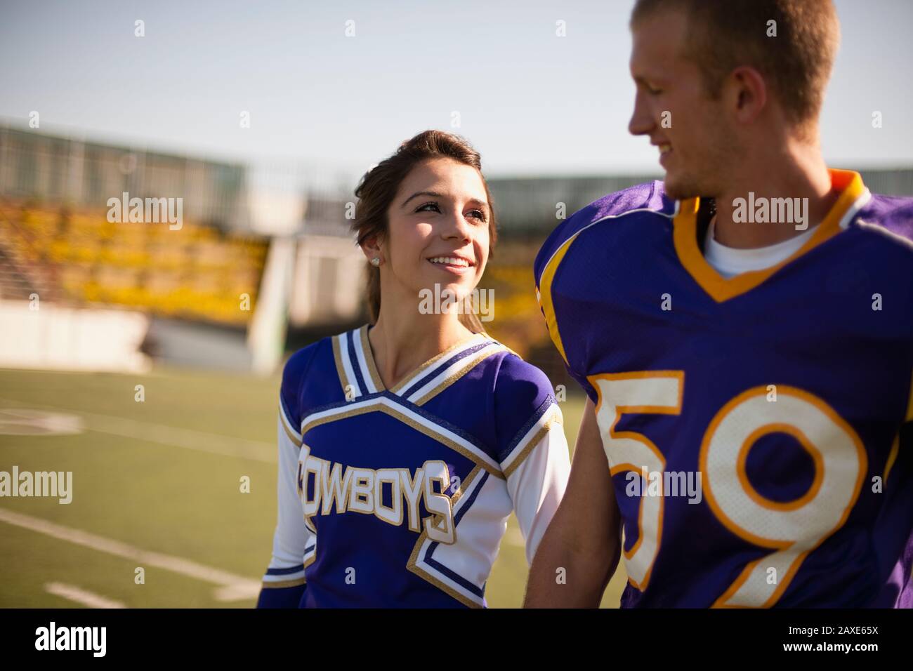 Giovane coppia Swoony, cheerleader e giocatore di calcio, guardandosi gli occhi l'uno nell'altro. Foto Stock