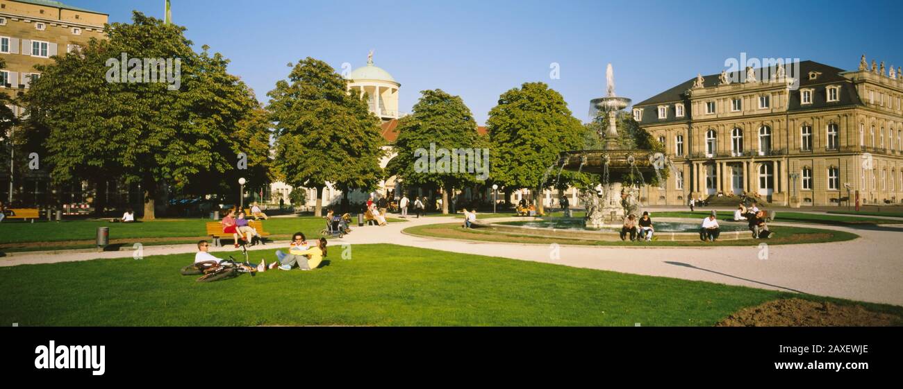 Gruppo Di Persone Sedute Intorno A Una Fontana In Un Parco, Schlossplatz, Stoccarda, Baden-Wurttemberg, Germania Foto Stock