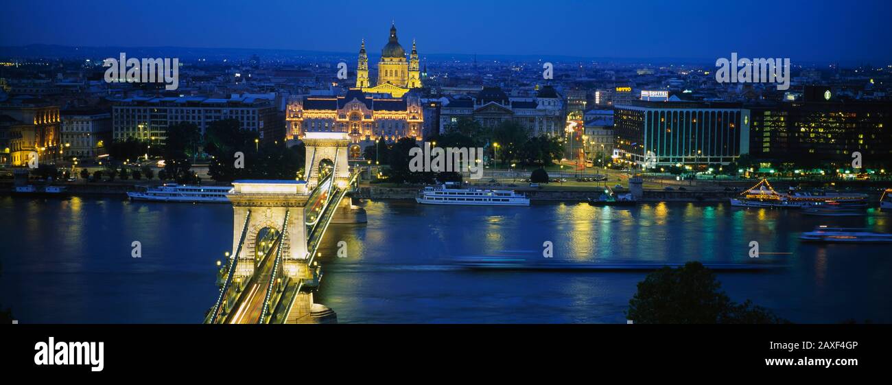 Vista ad alto angolo di un ponte sospeso illuminato al tramonto, Ponte delle catene, Danubio, Budapest, Ungheria Foto Stock