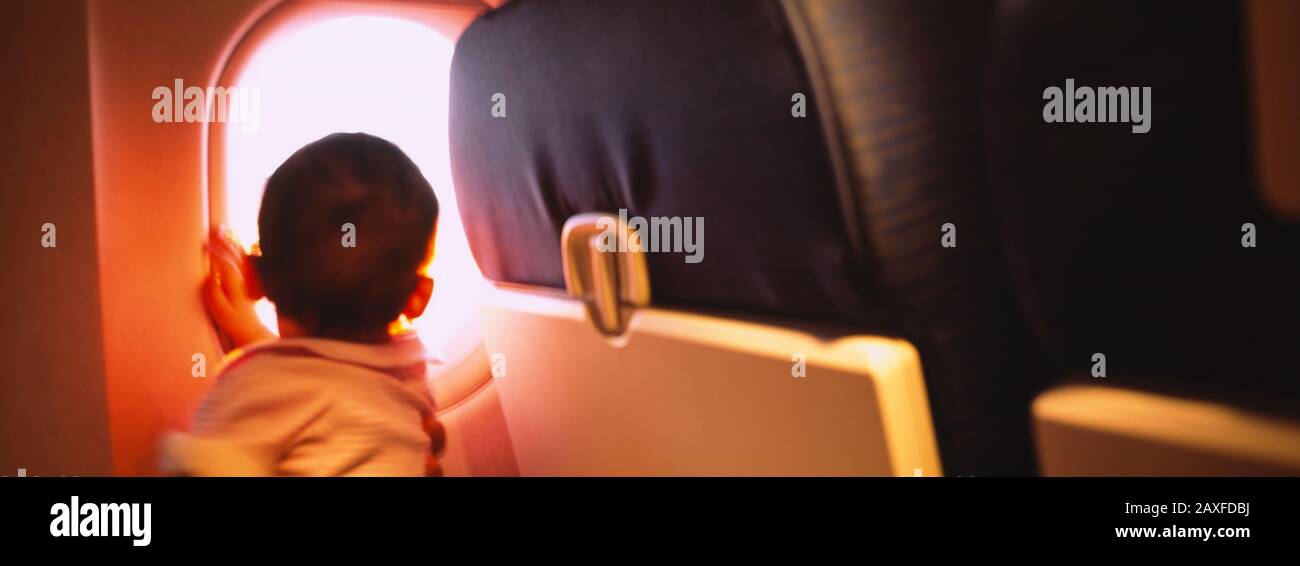Vista posteriore di un bambino che guarda attraverso una finestra di aeroplano Foto Stock