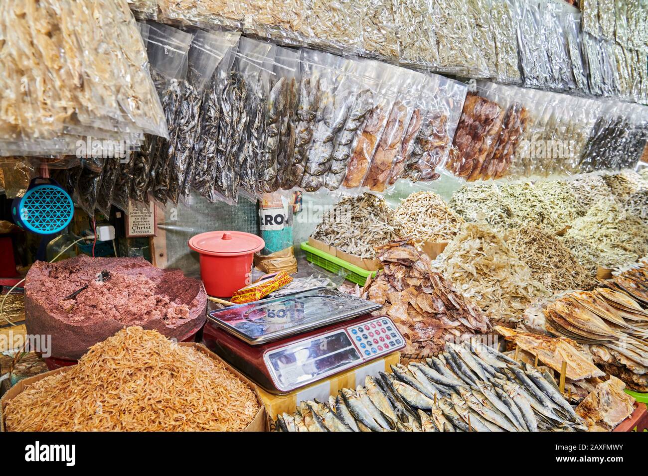 Primo piano di mucchi di piccoli pesci secchi e salati in cestini di bambù e sacchetti di plastig e pasta di gamberetti per la vendita in un mercato in Iloilo, Filippine, Asia Foto Stock