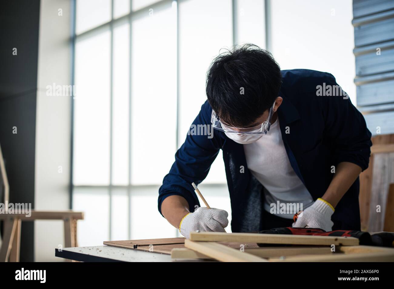 Asian man Carpenter che lavora con disegno tecnico o carta da costruzione di progetto che giace su un laboratorio con attrezzi di Falegnameria e legno nel paese Foto Stock
