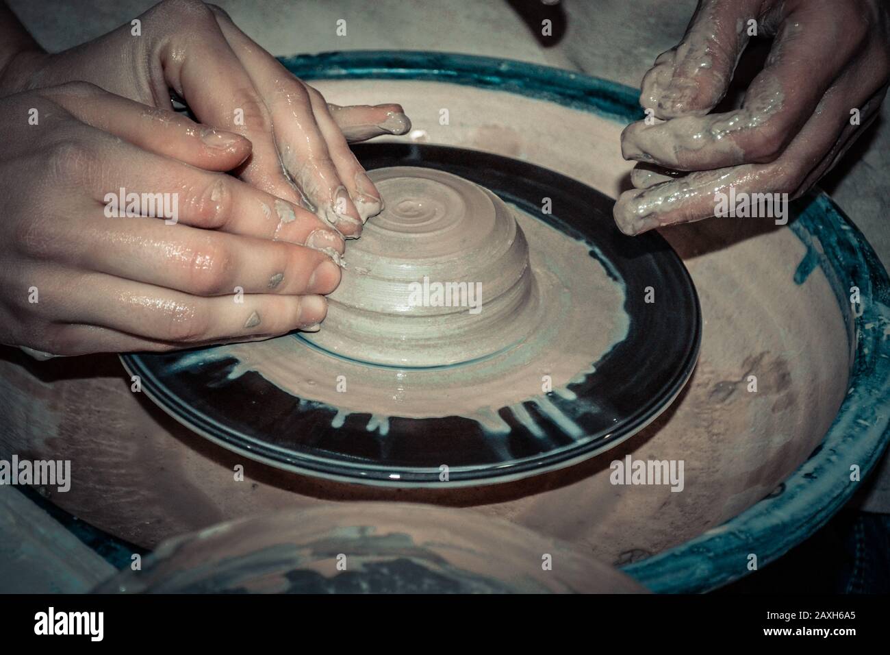 Un uomo con le mani dub muro brocca, che scolpisce fuori di argilla su un cerchio Foto Stock