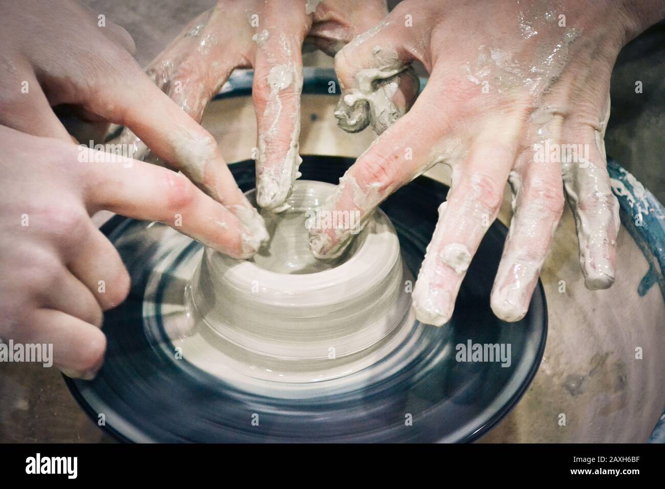 Un uomo con le mani dub muro brocca, che scolpisce fuori di argilla su un cerchio Foto Stock