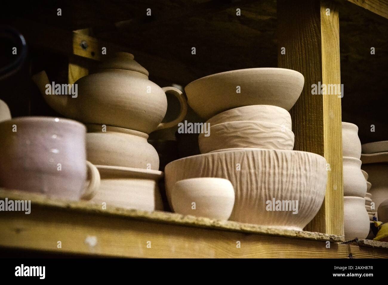 Ceramica brillante. Molte ceramiche bianche, non dipinte in terracotta, su scaffali di legno Foto Stock