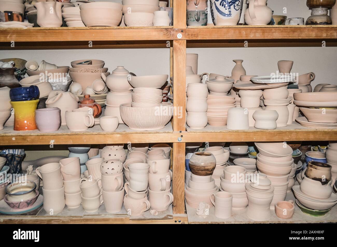 Ceramica brillante. Molte ceramiche bianche, non dipinte in terracotta, su scaffali di legno Foto Stock