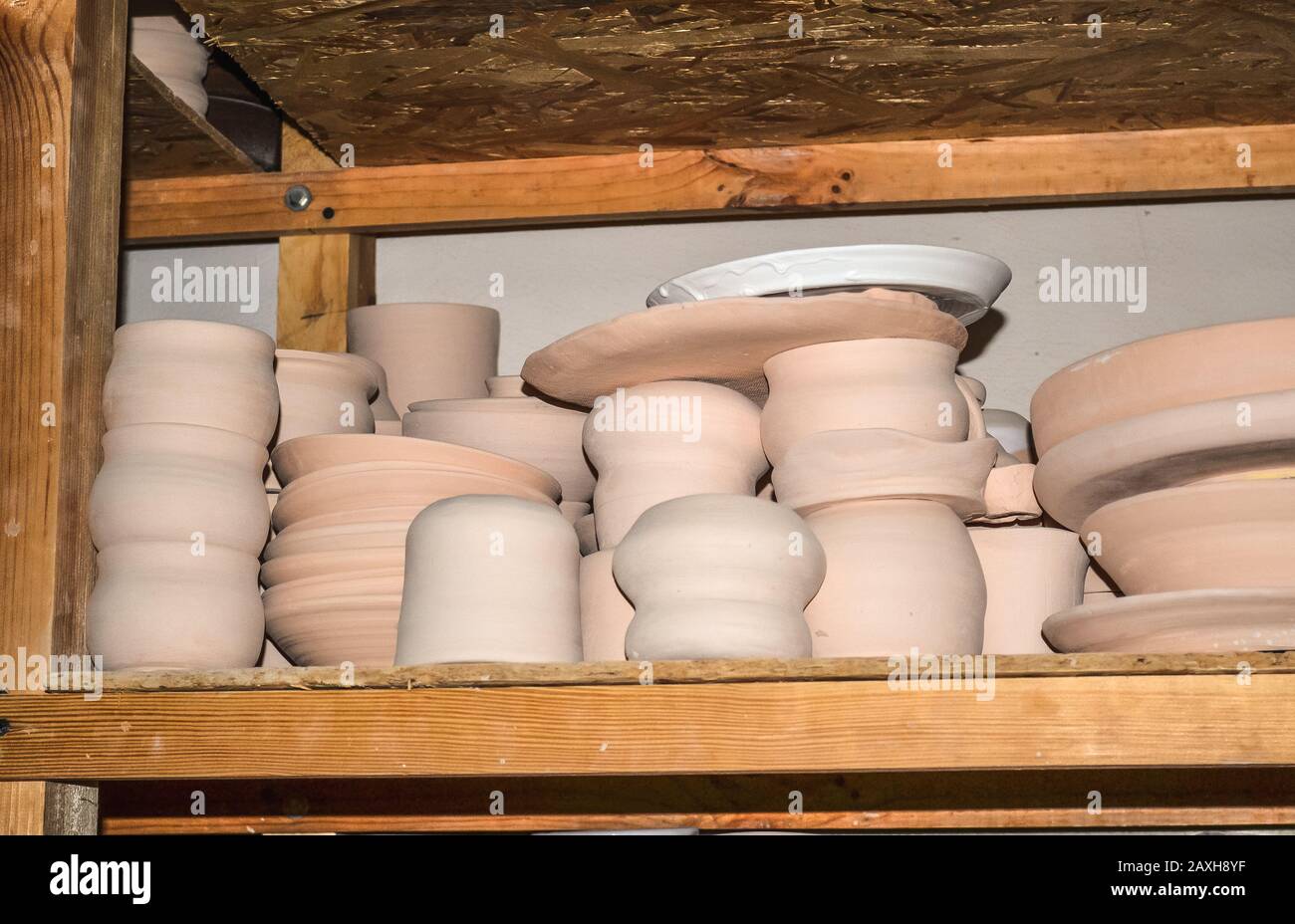 Ceramica brillante. Molte ceramiche bianche, non dipinte in terracotta, su scaffali di legno Foto Stock