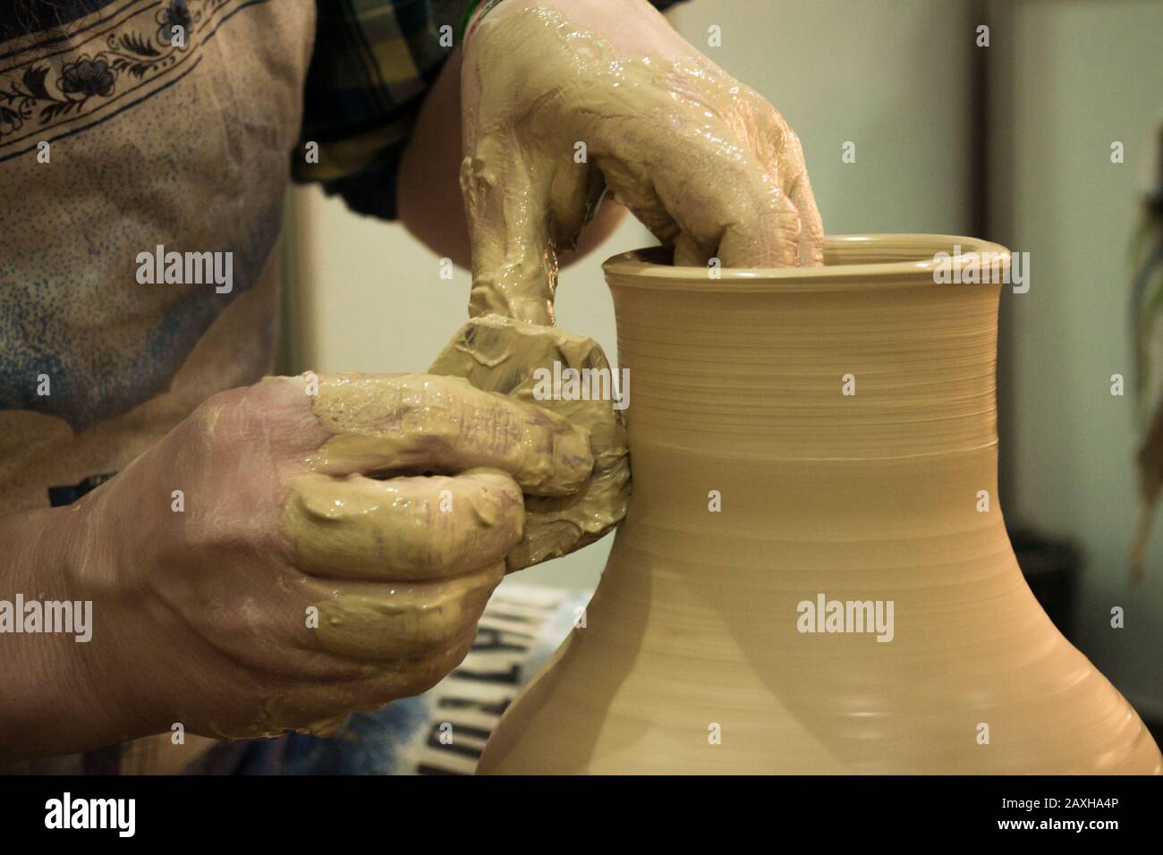 Il vasaio forgia il vasetto di argilla. Workshop su scultura closeup in argilla bianca. Mani sporche nell'argilla. Produzione di prodotti ceramici . Creatività artistica. Foto Stock