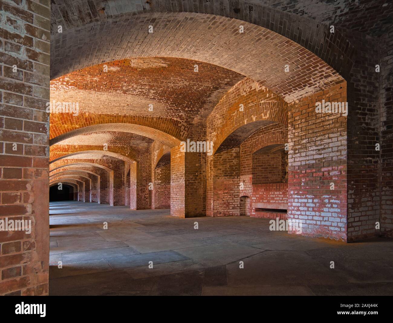 Un lungo corridoio apparentemente infinito in una fortezza con spesse mura in mattoni e archi in mattoni Foto Stock