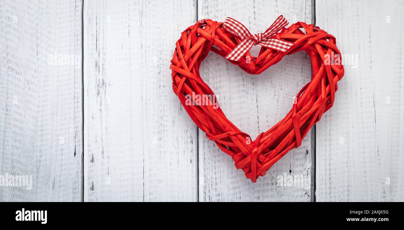 Cuore rosso dal nastro su sfondo bianco di legno, modello con spazio di testo. Piatto con concetto di amore, carta San Valentino, mockup. Decorazione layout. Fes Foto Stock