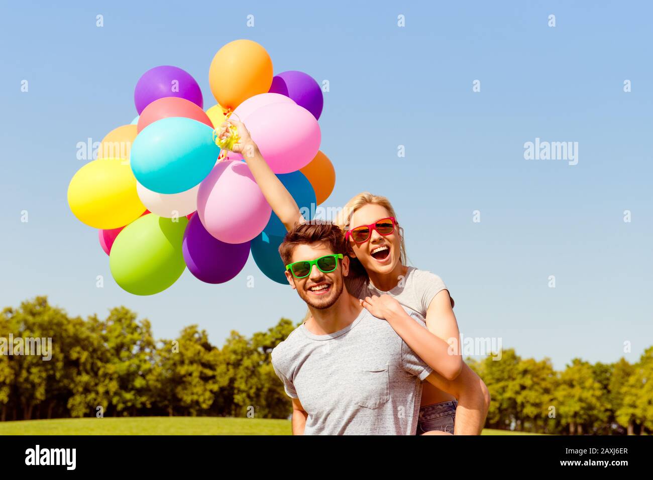 Ritratto di uomo felice con palloncini piggybacking la sua ragazza Foto Stock