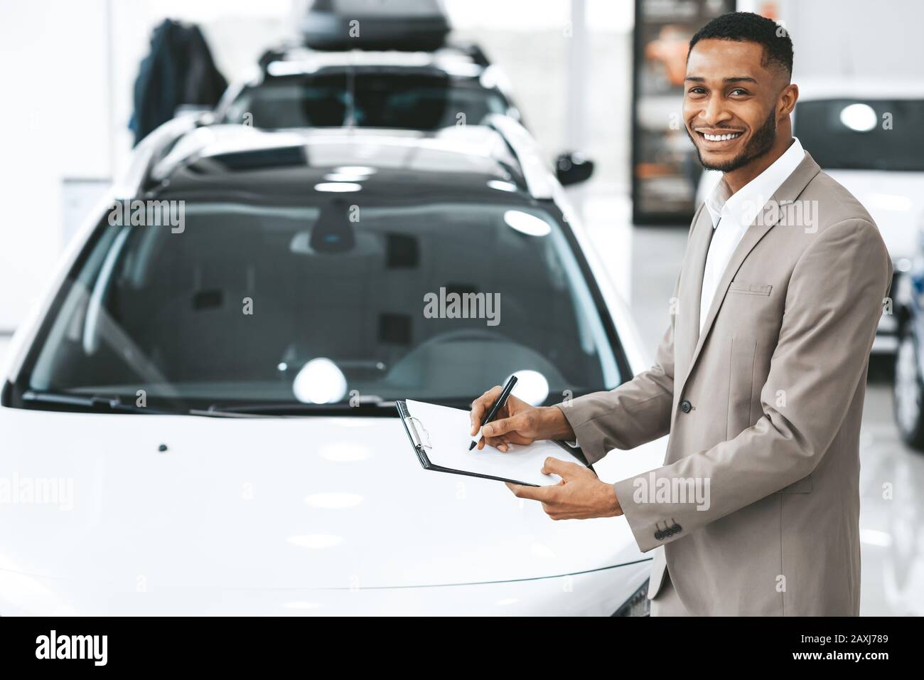 African American Salesman Selling Car Standing In Dealership Center Foto Stock