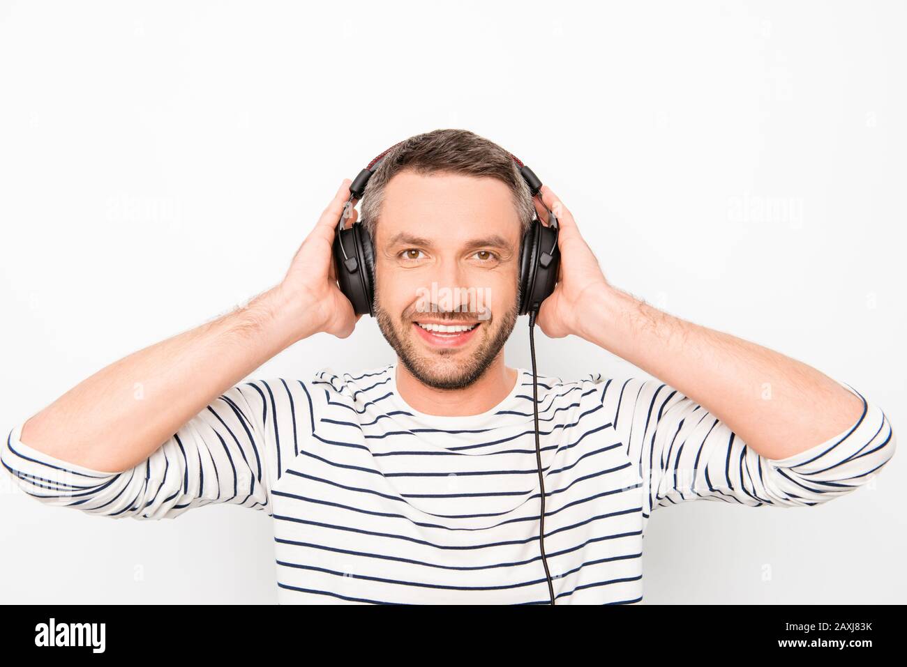 Ritratto di uomo sorridente felice toccando le cuffie e ascoltando musica Foto Stock