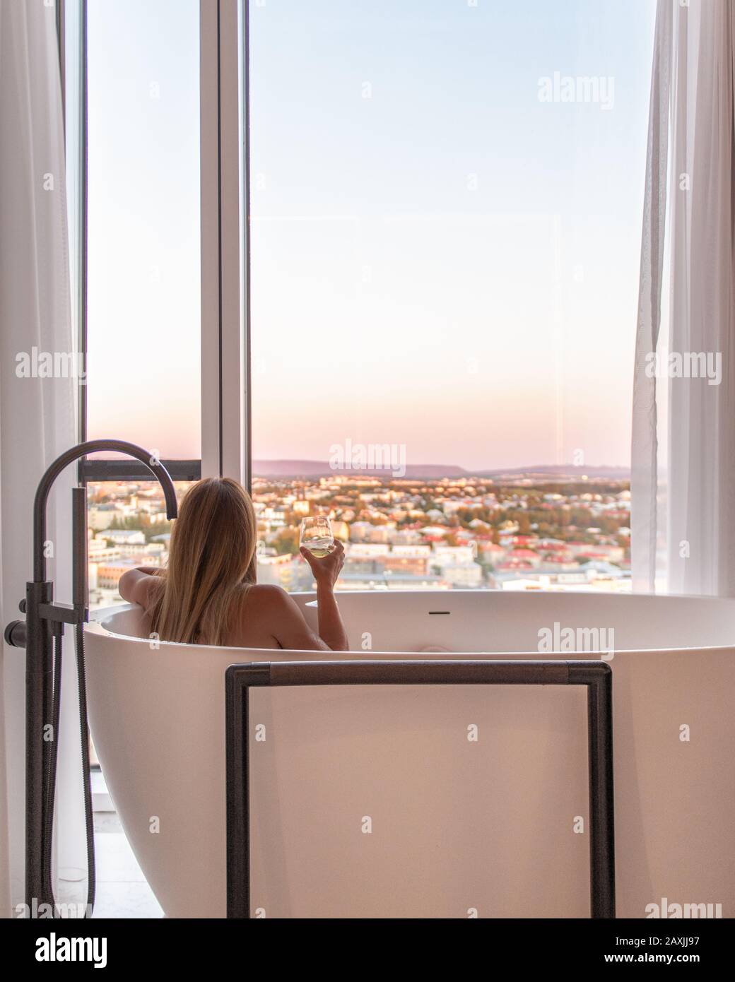 Donna in lussuoso hotel suite bagno con vista su Reykjavik Foto Stock