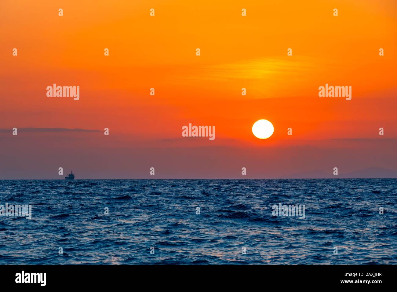 Mare sconfinato. Incredibile tramonto arancione. Piccola nave a bordo all'orizzonte Foto Stock
