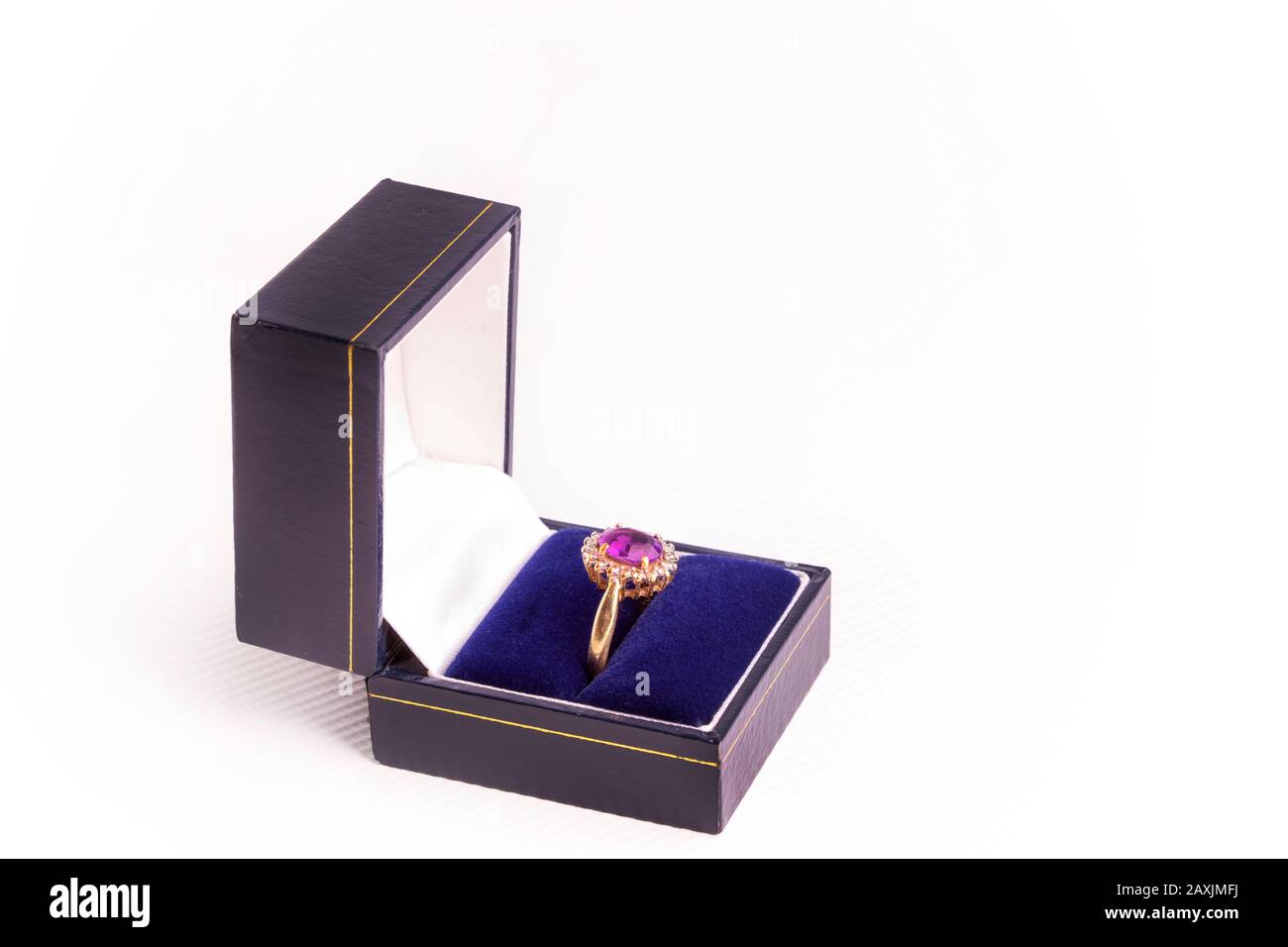 Un anello oro Signore con rubino e diamanti su uno sfondo bianco in una scatola blu. Foto Stock