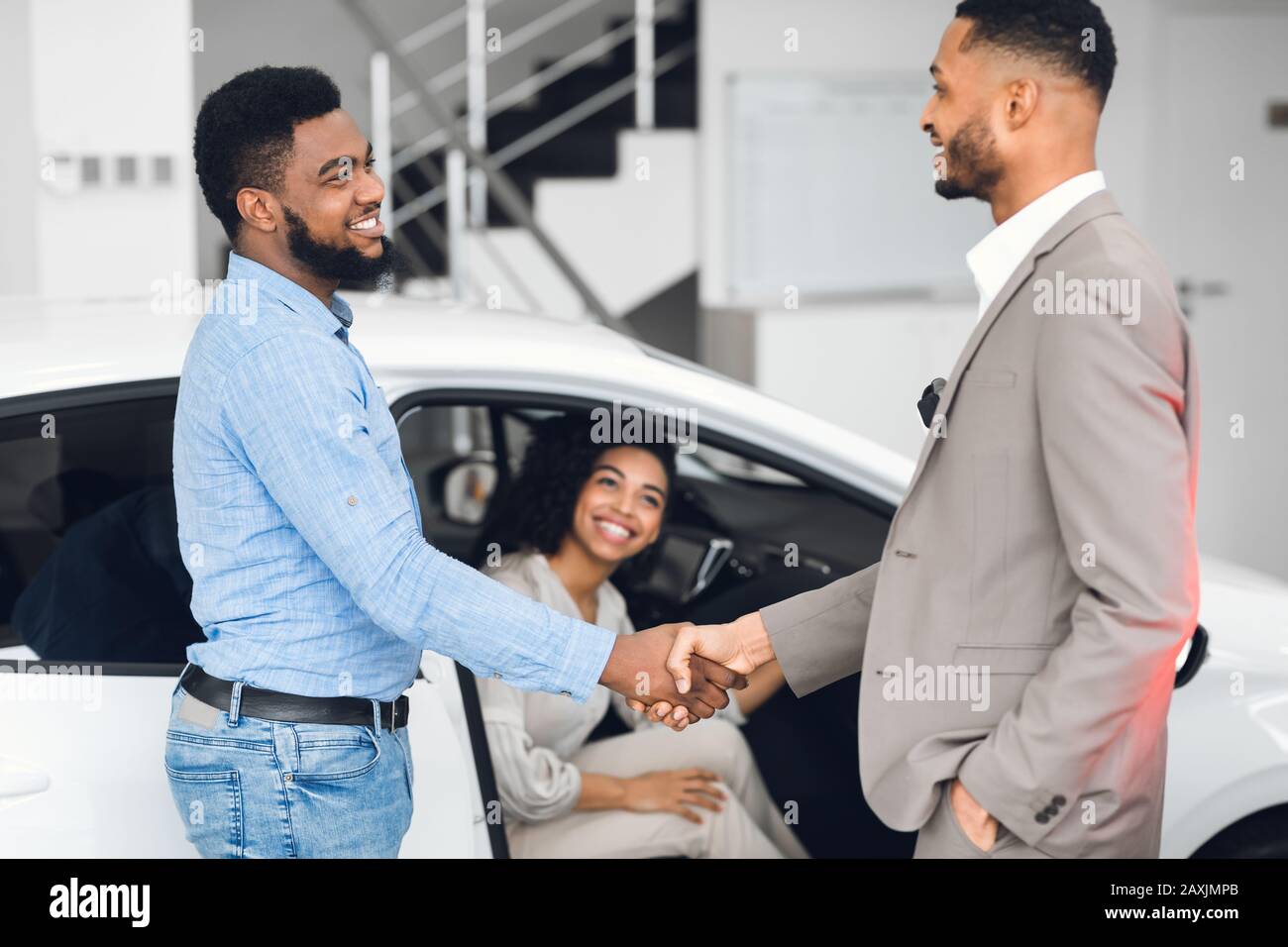 Uomo Che Si Stringe Le Mani Con Il Responsabile Delle Vendite Di Auto Nel Dealership Store Foto Stock