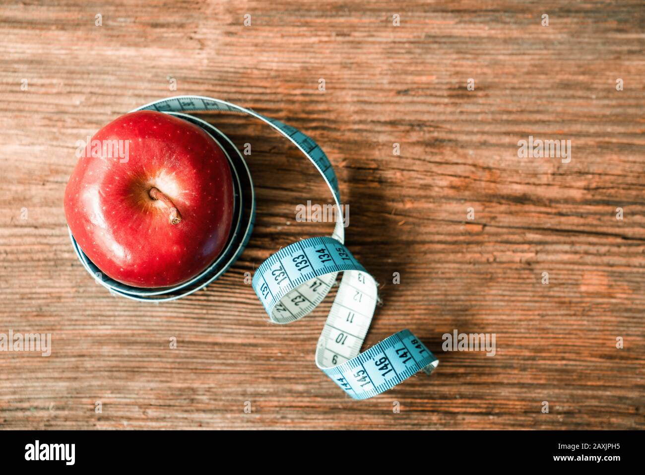 mela rossa isolata avvolta con nastro adesivo su fondo bianco. Dieta e sano concetto di vita Foto Stock