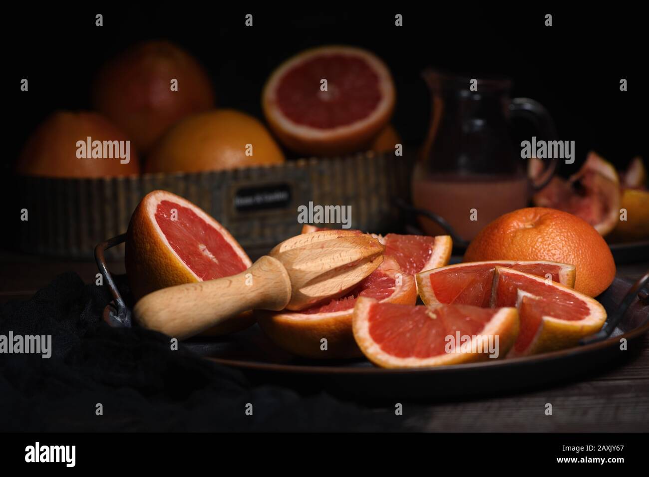 Fette di pompelmo fresco preparato per preparare spremuta fresca su un piatto, fondo scuro Foto Stock