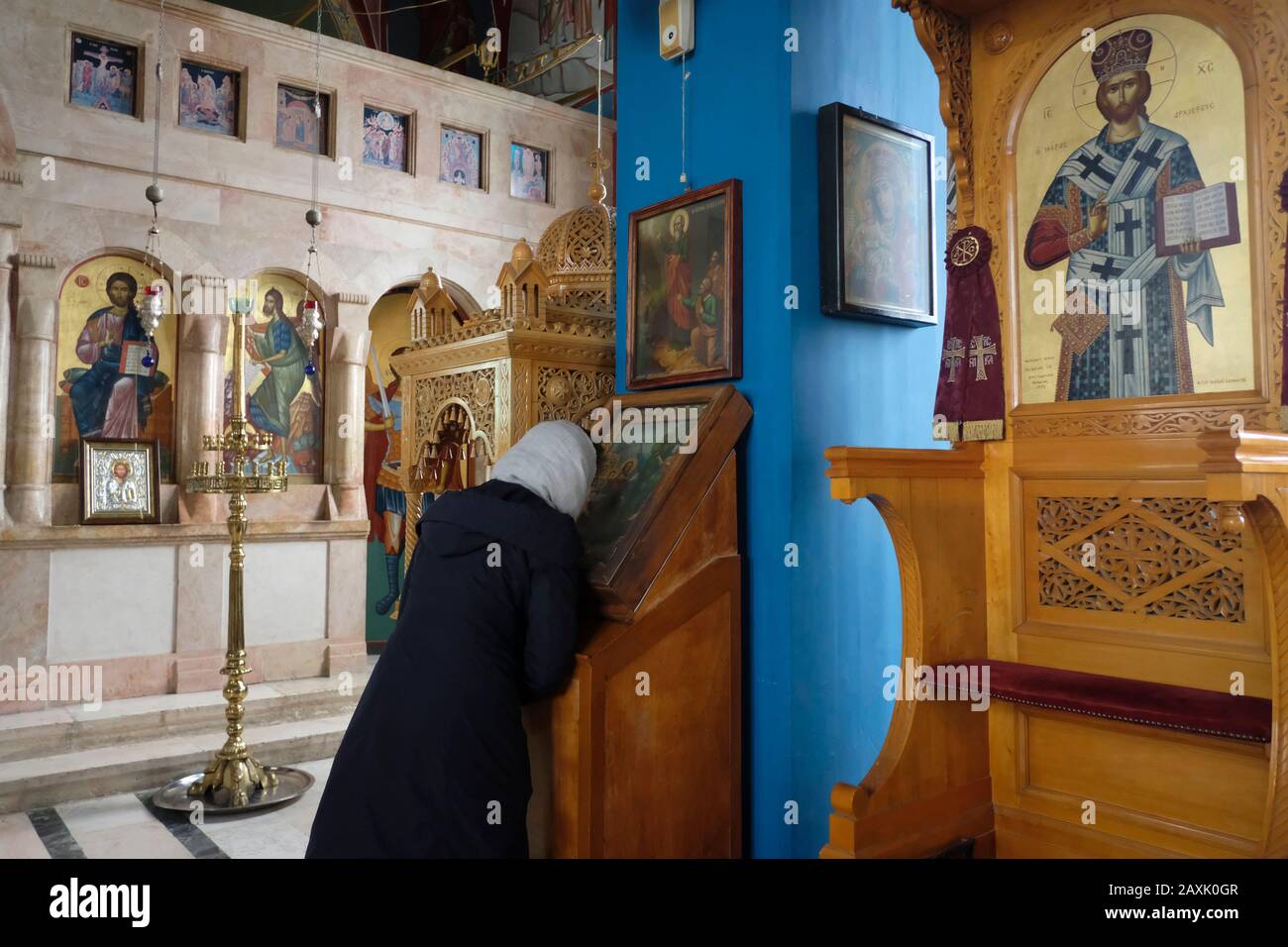 Pellegrino Ortodosso orientale bacia un'icona religiosa mentre prega all'interno della Chiesa Greco Ortodossa del profeta Eliseo nella città di Gerico nei territori palestinesi. Cisgiordania, Israele Foto Stock