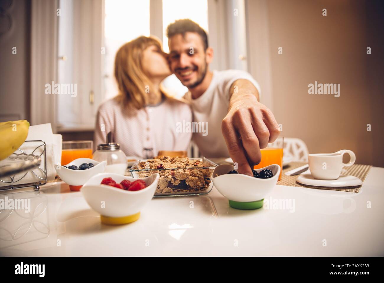 Giovane coppia felice seduta da tavolo con colazione insieme al mattino. Attenzione a portata di mano. Foto Stock